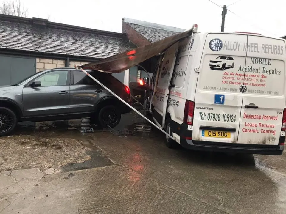 Repairing grey SUV under canopy